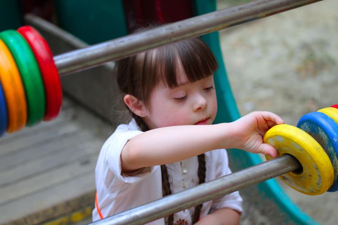 Young girl with serious expression playing with an abacus outside