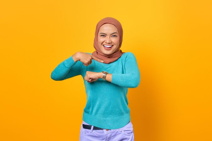 Happy Muslim woman pointing at her watch
