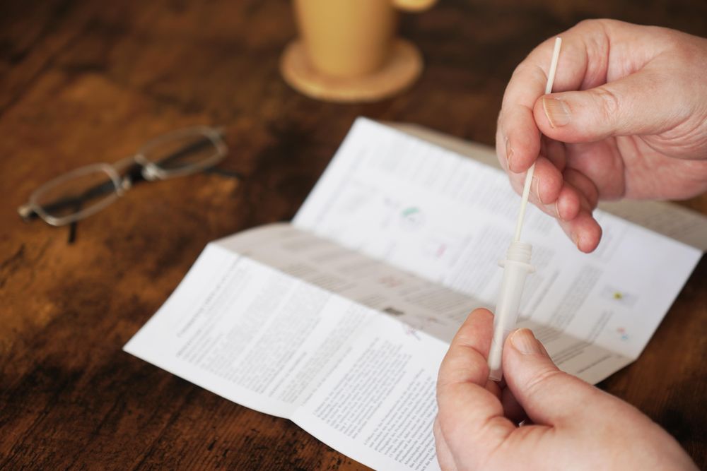 Person holding cotton swab for coronavirus antigen self-test at home