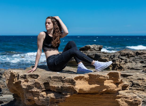 female relaxing on rocky seashore