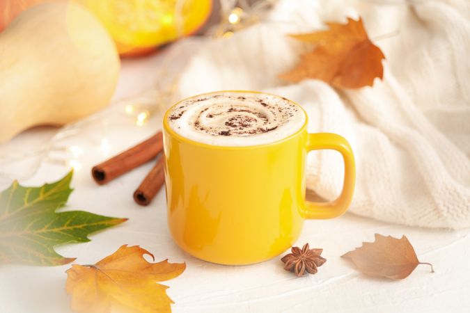Composition with cup of pumpkin latte on light background