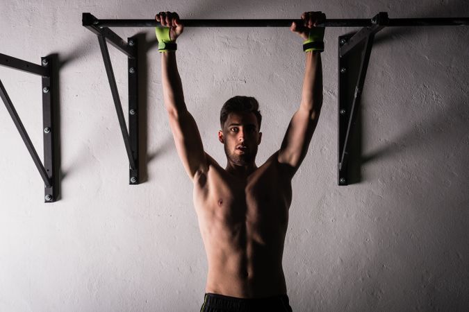 Man hanging on bar near wall in gym