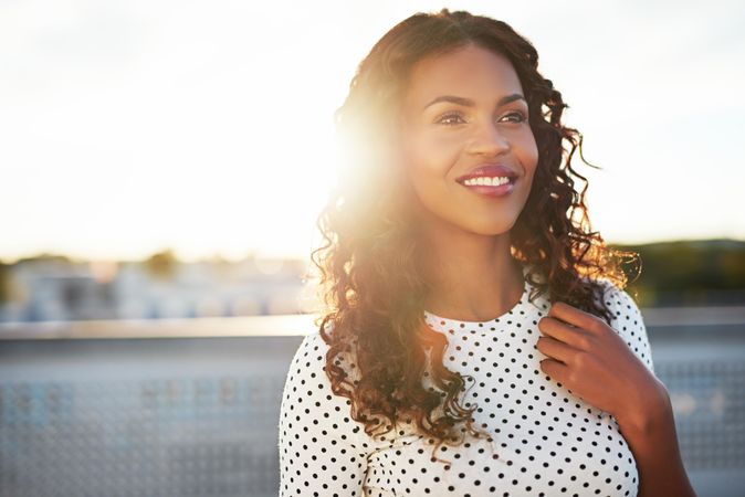 Smiling woman backlit by sun looking into the distance and smiling
