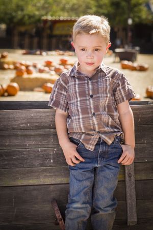 Boy Standing Against Old Wood Wagon at Pumpkin Patch in Rural Setting