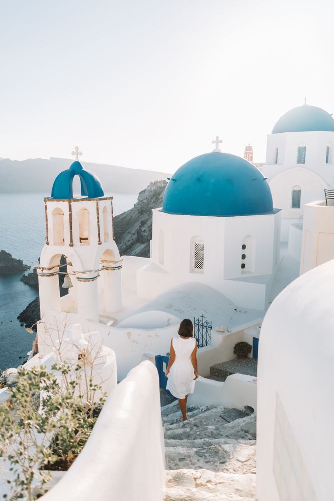 Woman walking on concrete stairs near Oia castle in Santorini, Greece 
