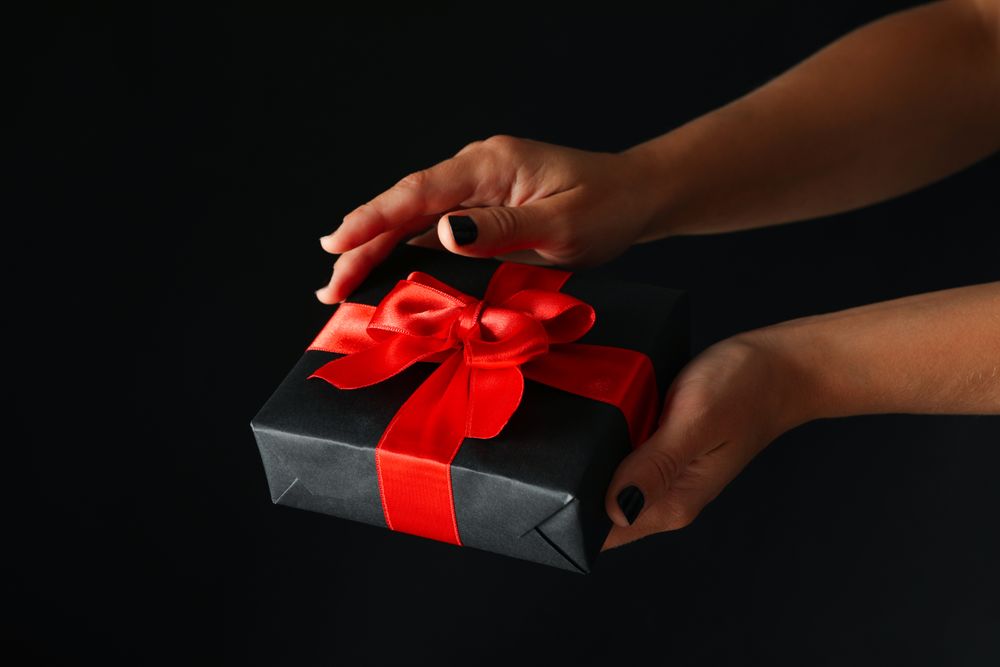 Female hands hold gift box on dark background