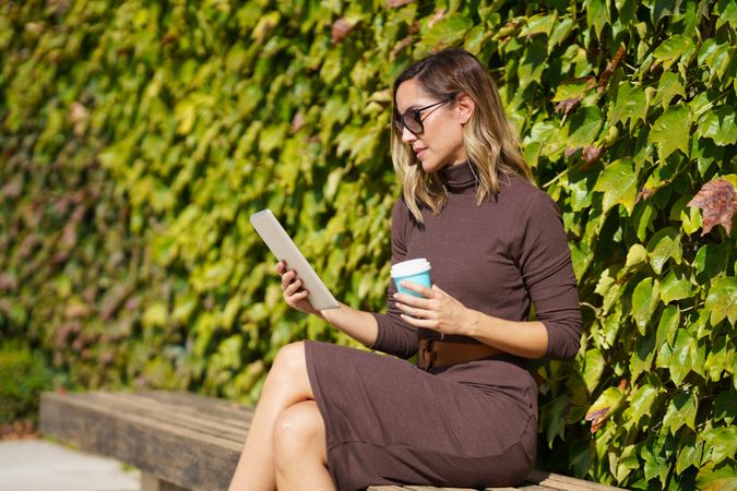 Side view of professional woman sitting outside with tablet