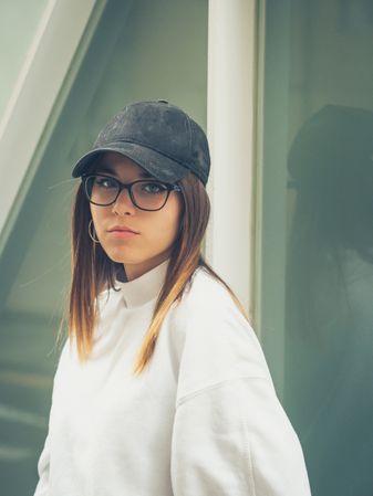 Young woman with glasses standing against wall