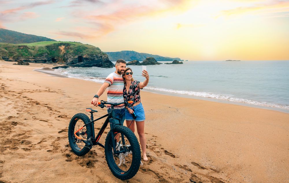 Male and female taking picture with phone standing with bicycle