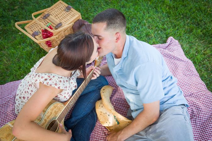 Young Adult Couple with Guitar Kissing in the Park.