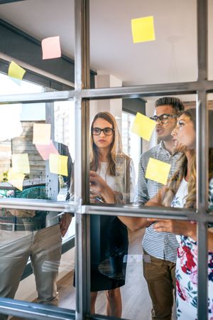 Business people in a work meeting placing sticky notes on the wall