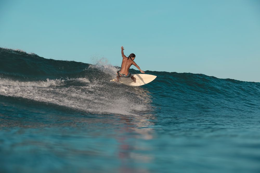 Man on surf board on waving water at sunset