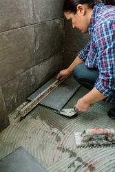 Female bricklayer checking floor with a level