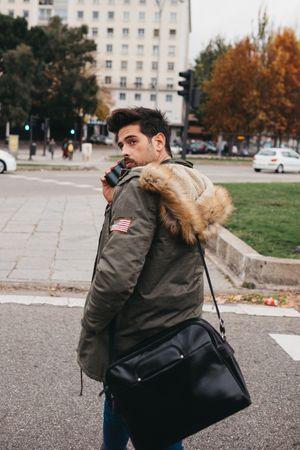 Busy male with smartphone crossing road