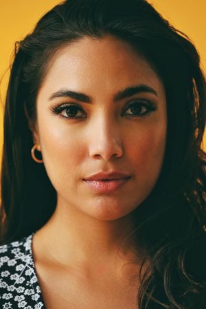 Headshot of serious Hispanic woman in yellow room, vertical