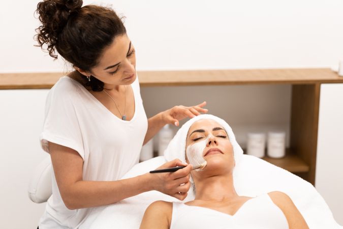 Female with towel on head having a relaxing face mask applied at spa