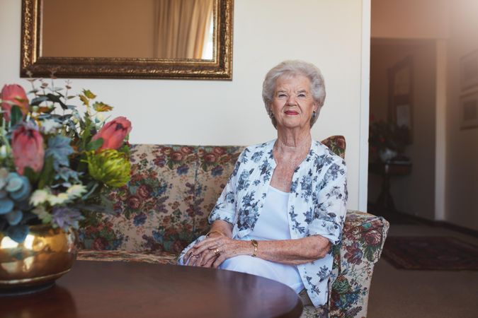 Happy older woman sitting on floral sofa