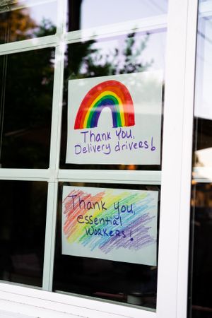 Hand lettered signs taped to home windows thanking essential workers during quarantine
