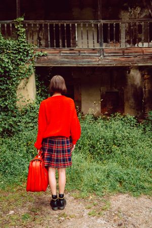 Woman in red with big red suitcase in forest