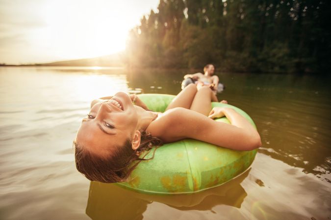 Closeup portrait of smiling young girl floating in an innertube with a man in the background