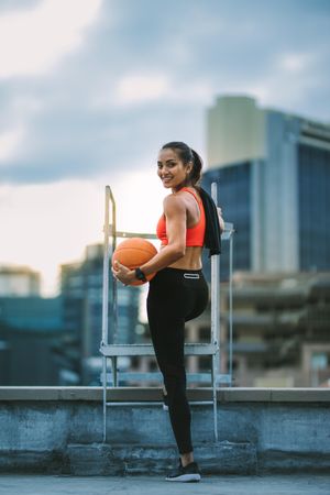 Rear view of a woman in fitness wear standing on rooftop doing fitness training