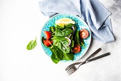 Top view of leafy spinach salad with lemon slice