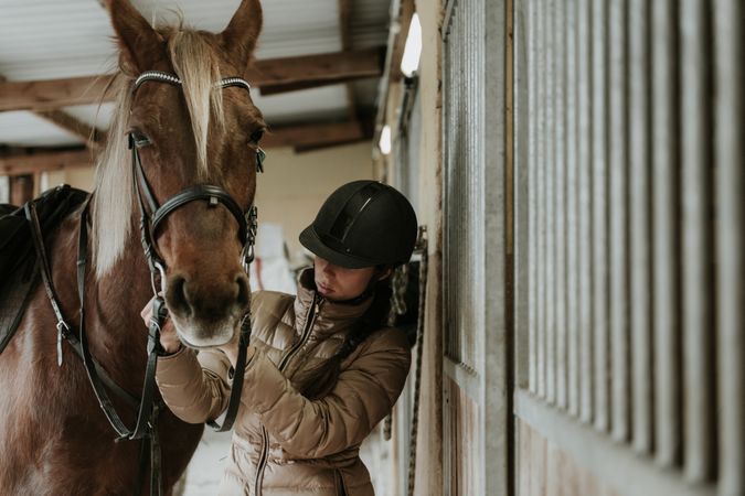 Woman putting saddle on horse