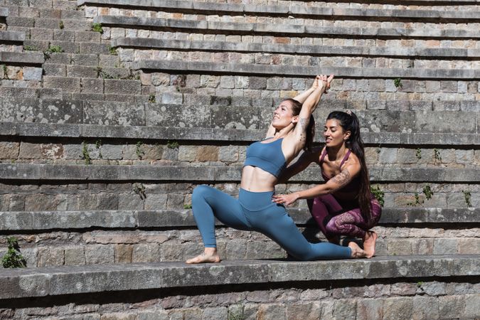 Instructor helping woman doing yoga in low lunge pose