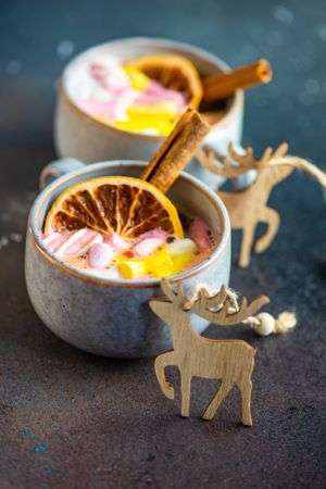 Two cups of marshmallow drinks with cinnamon and dried orange slice