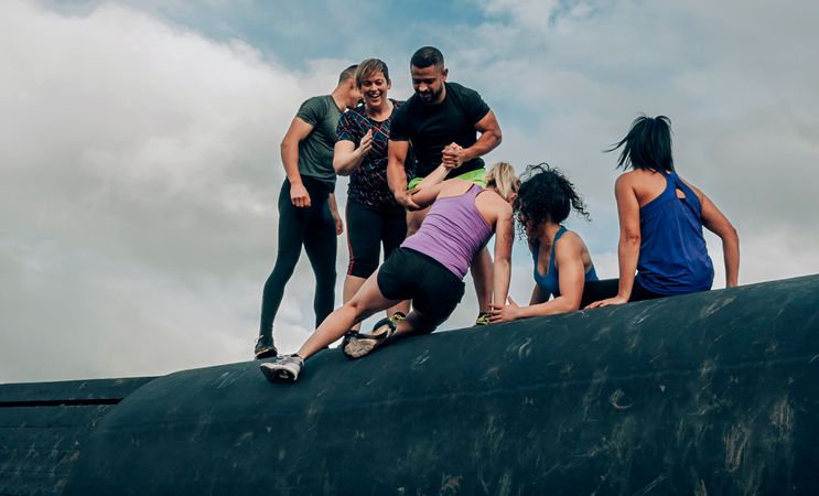 Participants in obstacle course climbing a drum