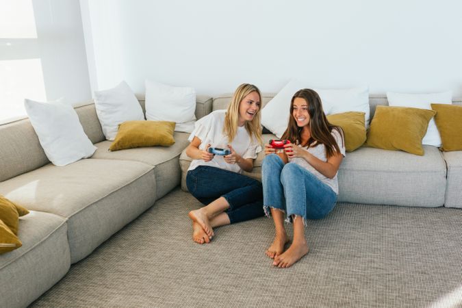 Cheerful women playing videogame on couch