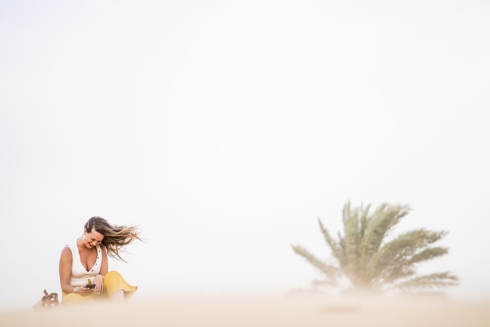 Happy woman using smartphone in desert
