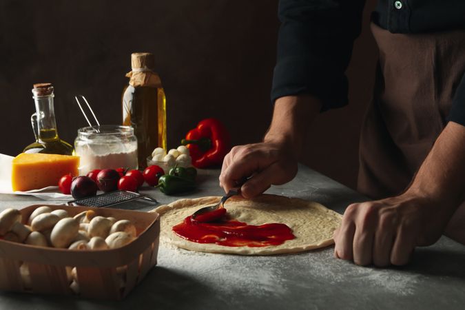 Man cooking pizza on gray table with ingredients