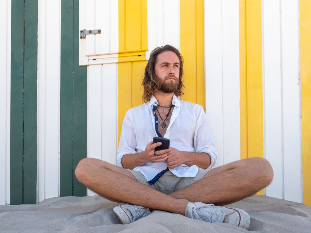 Cheerful guy using smartphone near striped wall