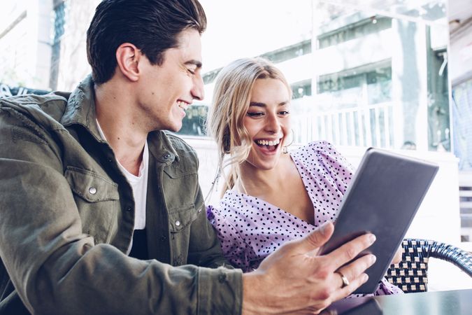 Happy young couple using tablet outdoors