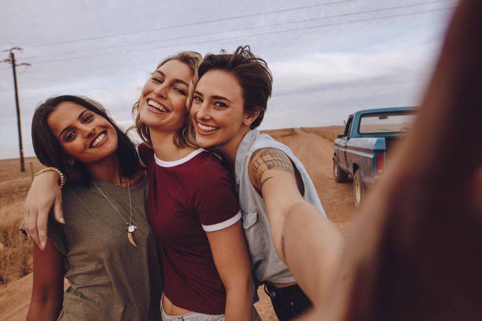 Group of happy young women taking selfie while on road trip