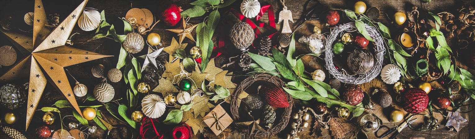 Holiday decorations of stars, baubles, leaves, scissors and ribbon, wide composition
