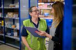Two women talking with clipboard in warehouse