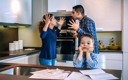 Man and woman with hands up in frustration as they argue in front of their son