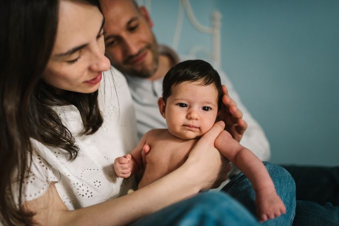 Parents hugging baby on bed