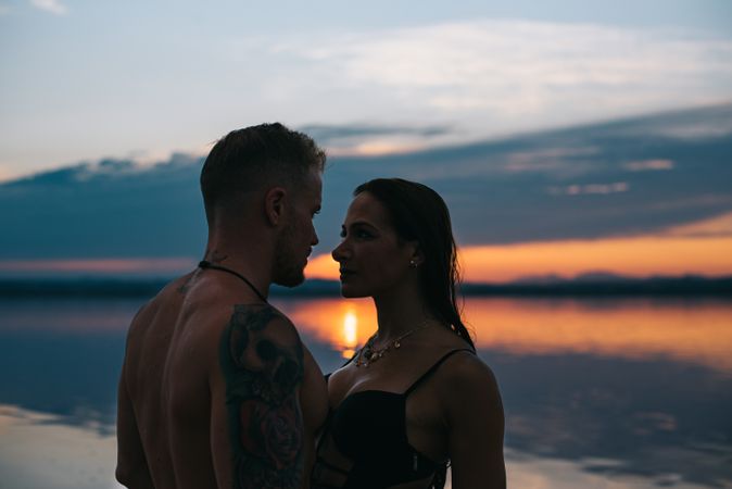 Couple hugging on beach of lake at sunset