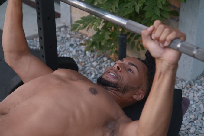 Black guy lifting barbell on street