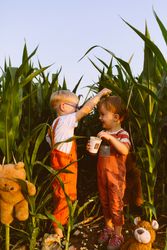 Cute little brother playing together in green corn field