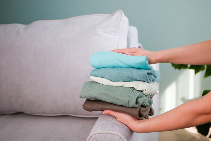 Pile of colorful warm clothes on the grey sofa.