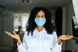 Portrait of confident woman in facemask with her arms up