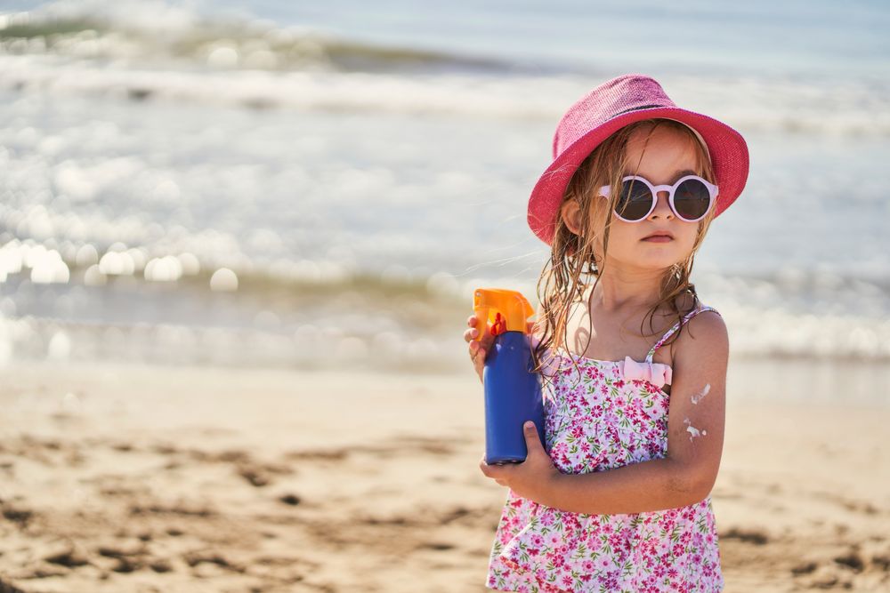 portrait of a girl with a bottle of sunscreen on the beach