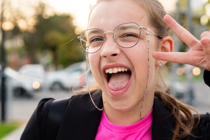 Girl giving peace sign and yelling in excitement.