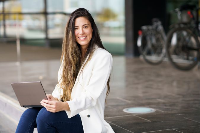 A young professional woman cheerfully working diligently on her laptop in an outdoor setting