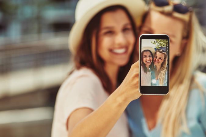 Women smiling and taking selfie on sunny day
