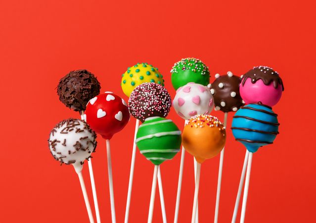 Multicolored cake pops isolated on a red background